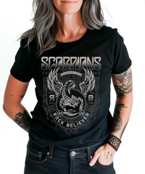 Scorpions "Rock Believer" ozdoby z motywem orła i gitary, kolor czarny, trzymane w ręce przez osobę w spodniach.