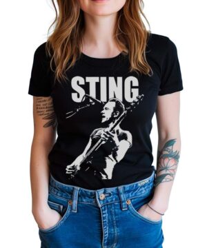Czarna koszulka muzyczna STING "AXE" z logo STING i grafiką gitarzysty, prezentowana na kobiecie w jeansach.
