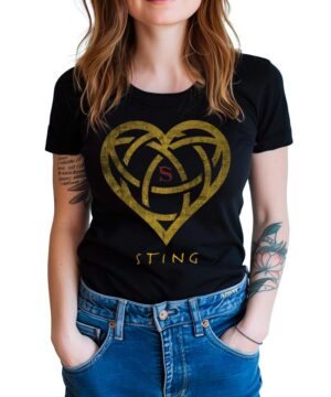 Czarna koszulka STING Heart z nadrukiem złotego serca, czerwonym S i napisem "STING"; kobieta z rękami w kieszeniach jeansów.