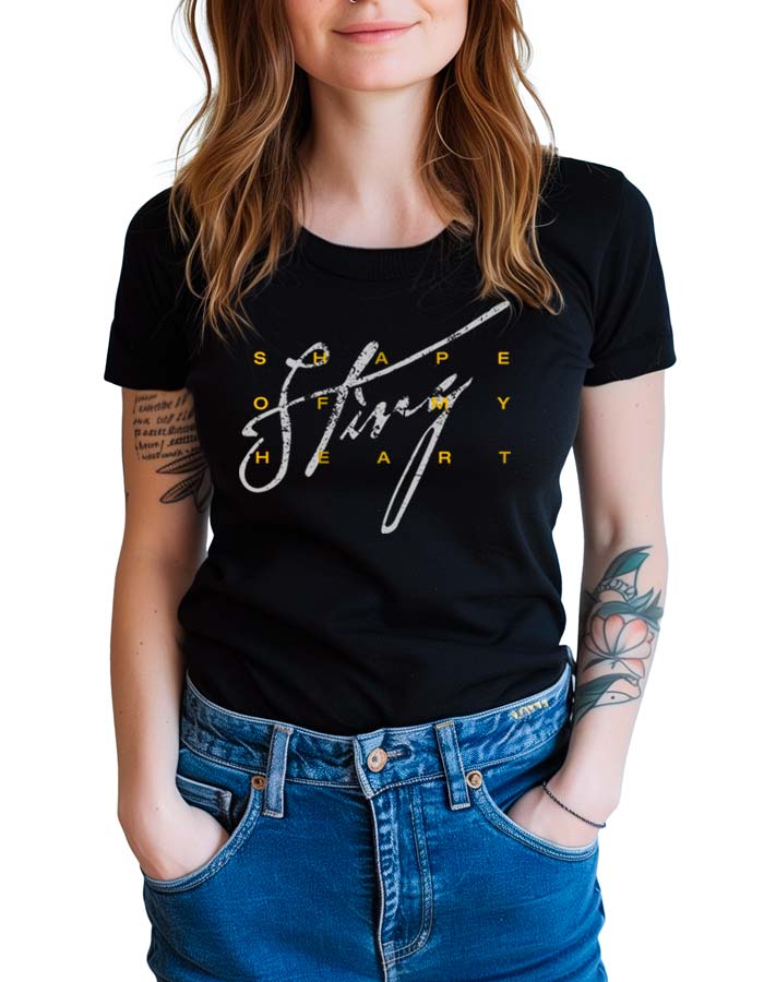 Czarna koszulka muzyczna STING "Shape of my heart" zakładana przez kobietę, widoczne tatuaże na rękach i niebieskie jeansy.