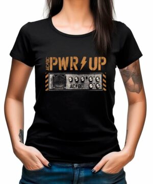 Kobieta ubrana w czarną koszulkę ACDC "PWR UP Knobs" z grafiką wzmacniacza, z rękami w kieszeniach.
