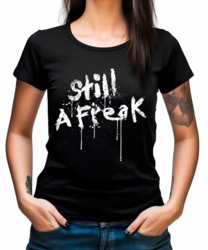 Czarna koszulka muzyczna KORN "Still a Freak" z białym nadrukiem, prezentowana przez osobę stojącą z rękami w kieszeniach.