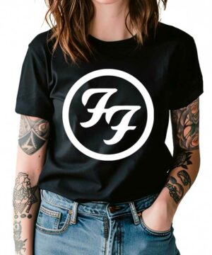 Kobieta z wytatuowanymi ramionami i niebieskimi dżinsami nosi czarną koszulkę damską FOO FIGHTERS "Logo" z logo zespołu FF w białym kółku z przodu.