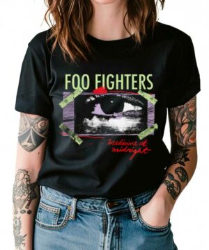 Osoba ubrana w czarną koszulkę FOO FIGHTERS "Medicine at midnight" z grafiką oka, w połączeniu ze zwykłymi niebieskimi dżinsami.