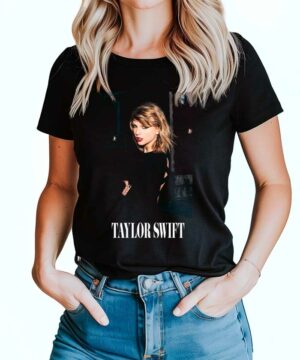 Czarna koszulka muzyczna TAYLOR SWIFT "City Nights" z nadrukiem blondynki i napisem na froncie, noszona przez kobietę w jeansach.