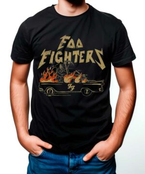 Osoba ubrana w czarną koszulkę FOO FIGHTERS "Joyride" z płonącym samochodem i logo zespołu, ręce w kieszeniach dżinsów.