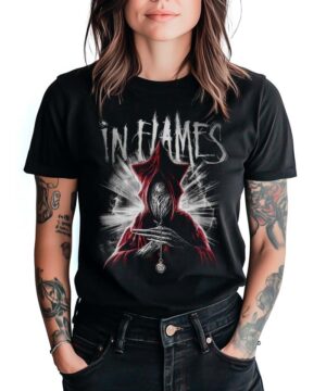 Czarna koszulka IN FLAMES "At the end" z grafiką zakapturzonej postaci i wisiora, widoczna na tle białym, prezentowana przez osobę z tatuażami.