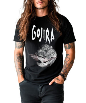 Osoba z długimi włosami i tatuażami nosi czarną koszulkę zespołu GOJIRA "Flying whale", stojąc z rękami w kieszeniach na białym tle.