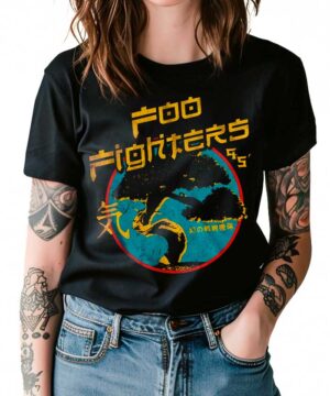 Osoba ubrana w czarną koszulkę damską FOO FIGHTERS "Bonsai" z żółto-niebieską grafiką i japońskim tekstem, stojąca z rękami w kieszeniach dżinsów.