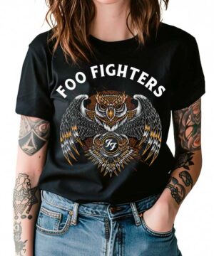 Osoba ubrana w czarną damską koszulkę FOO FIGHTERS "Owl" z ilustrowaną sową i logo zespołu, stojąca z rękami w kieszeniach.