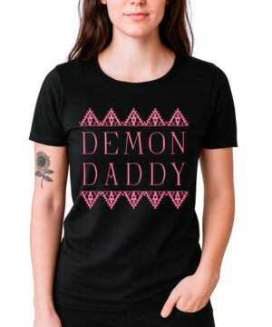 Kobieta ubrana w koszulkę damską FLORENCE AND THE MACHINE "Demon Daddy" - czarną koszulkę z różowym napisem i geometryczną ozdobną obwódką.