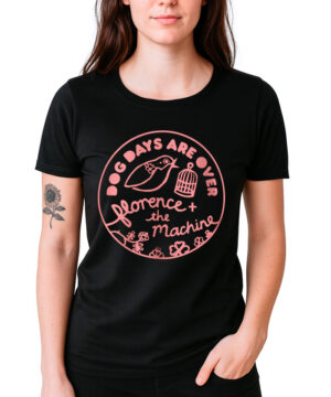 Osoba nosi koszulkę damską FLORENCE AND THE MACHINE "Dog days" - czarny t-shirt z różowym okrągłym nadrukiem Dog Days Are Over Florence + the Machine oraz grafiką ptaka i klatki dla ptaków.