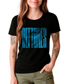 Kobieta ubrana w czarną koszulkę damską DEFTONES "Around the Fur halftone logo" z pogrubionym niebieskim napisem, stojąca z jedną ręką w kieszeni.